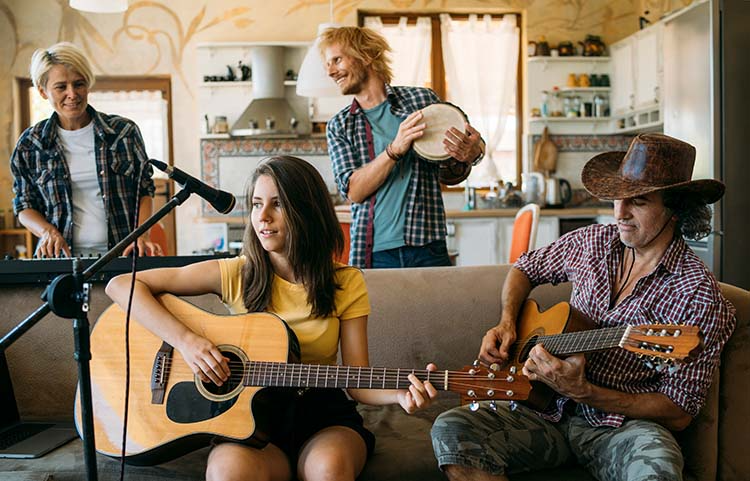 Group of people playing and recording music in a small apartment living room.